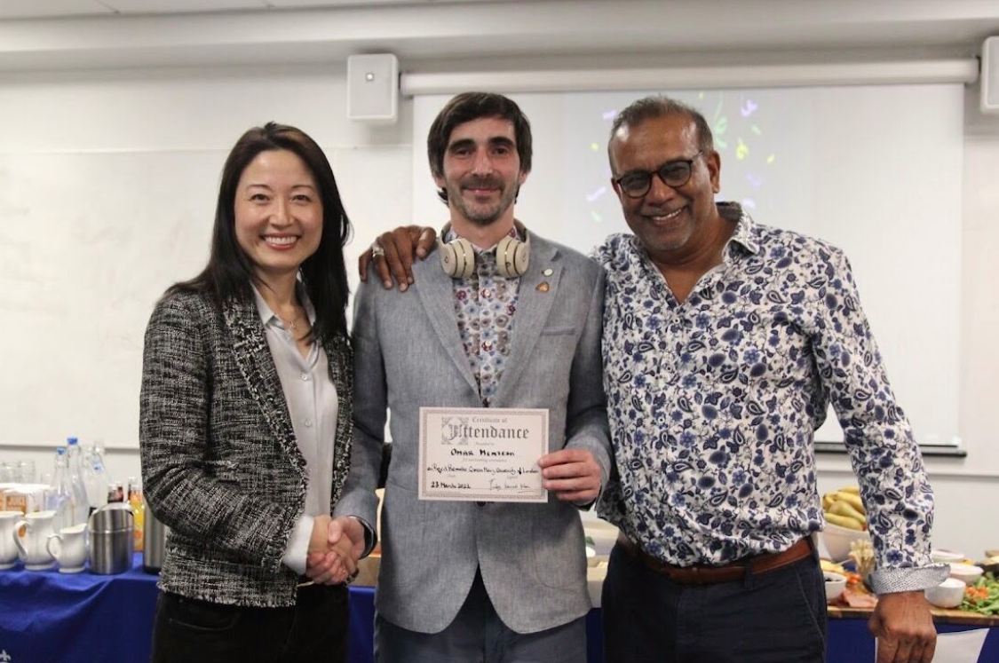 Omar Mentesh holding his certificate of completion, alongside Dr Joanne Zhang and Judge Kameel Khan