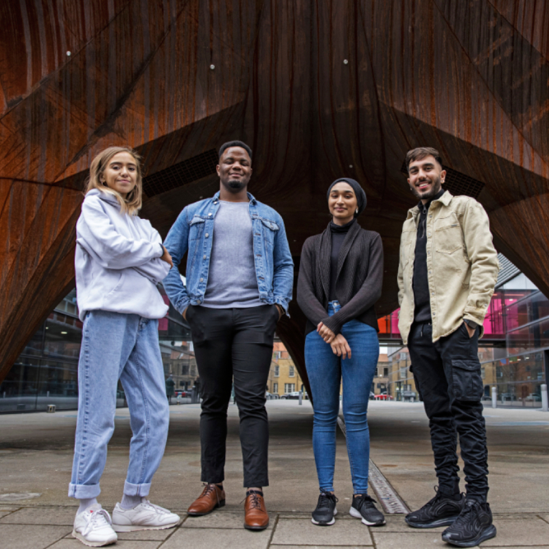 Students standing in front of a wooden statue