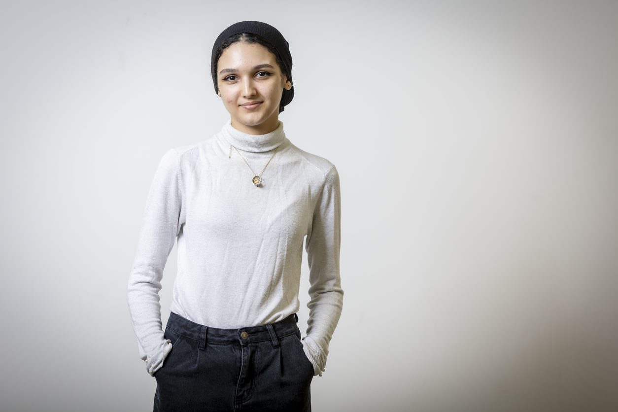 A student smiling at the camera, in a white poloneck