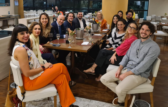 A group of 13 people sat at a bar table having drinks.