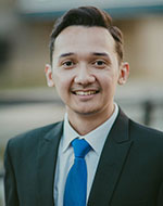 Antonius Tigor in a black suit and blue tie