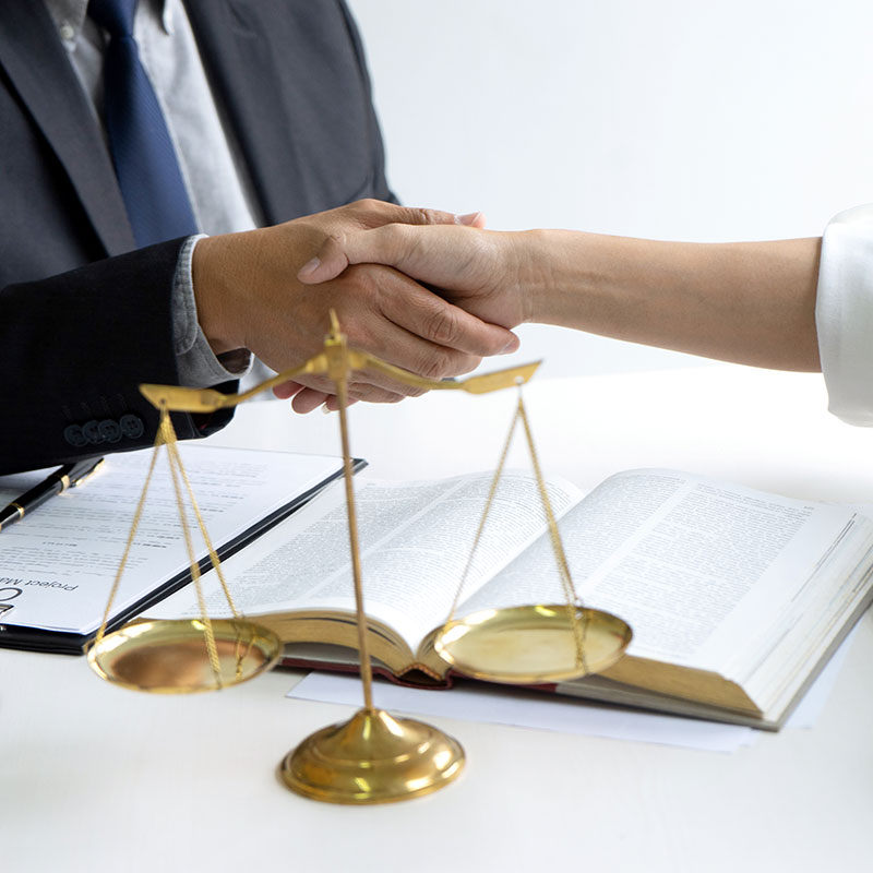 A man and woman shaking hands next to a pair of gold scales