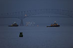 The Francis Scott Key Bridge bridge in Baltimore before it collapsed on 26 March 2024. It is a steel frame truss bridge spanning the lower Patapsco River. There are three ships in the river.