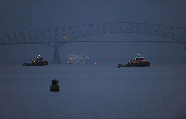 The Francis Scott Key Bridge bridge in Baltimore before it collapsed on 26 March 2024. It is a steel frame truss bridge spanning the lower Patapsco River. There are three ships in the river.