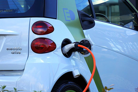 Taillights on the back on a white electric car that is plugged in charging