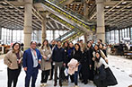 Queen Mary Insurance Law LLM students inside Lloyd's of London. Is is a multi-story office space with central escalators lit in yellow.