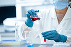 A medical tester wearing PPE pouring liquid between test tubes