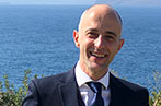 Professor Ioannis Kokkoris standing against a backdrop of the ocean.