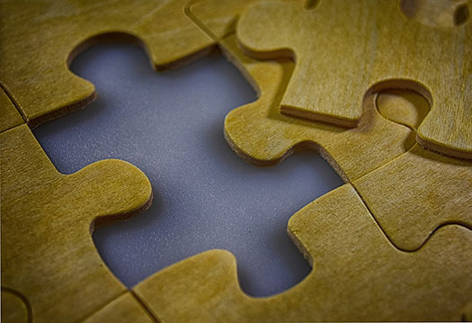 A wooden puzzle, with a missing piece being slotted in