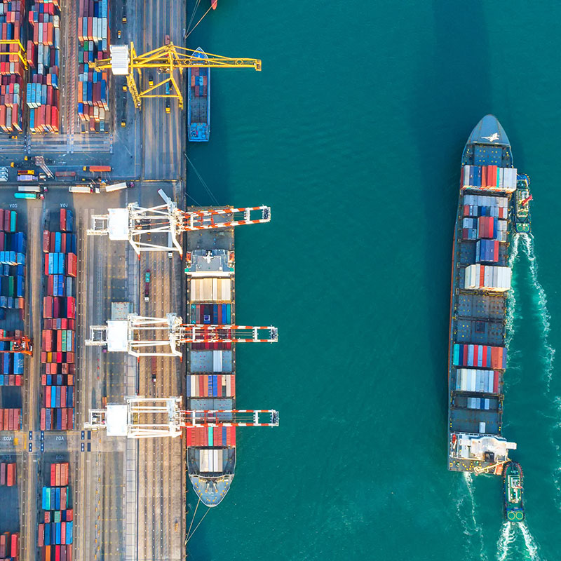 A shipping port with shipping containers and a ship pulling away from the port