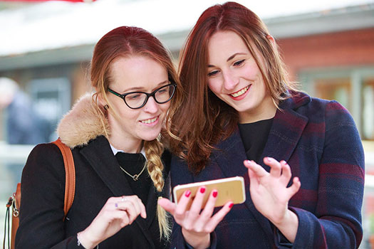 Students at CCLS reading on a smart phone