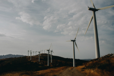 A hilly landscape with a row of wind turbines against a cloudy sky.