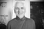 Black and white photo of J.A.L Sterling smiling standing next to a book case