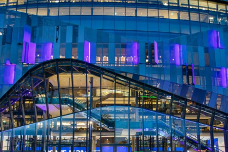 Photo of the exterior of Tottenham Hotspur Stadium illuminated at night