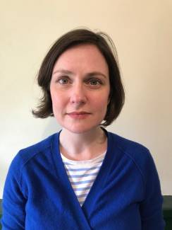 A woman with brown hair and a blue cardigan