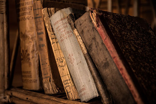 Old, worn books arranged on a shelf