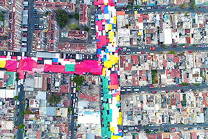 An aerial shot of tower blocks in a city, with colourful awnings on the streets.