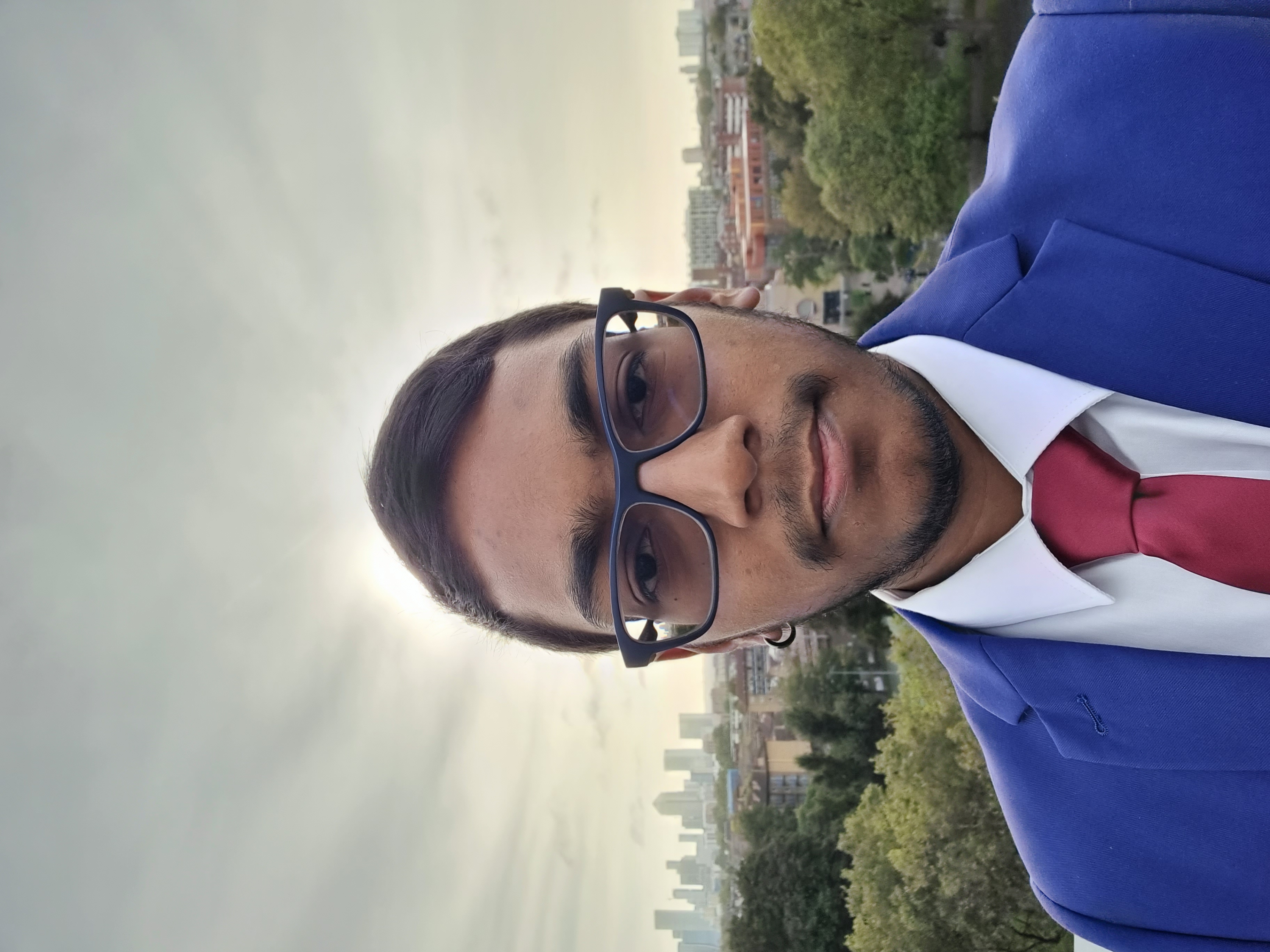 Headshot of student in a suit with the London skyline in the background