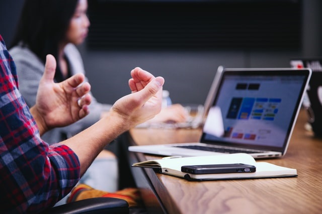 A photo of hands in front of a laptop