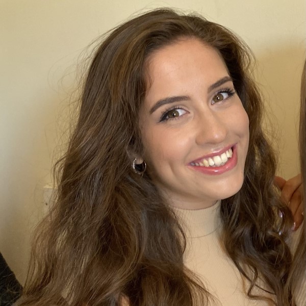 Headshot of alumna, Alice Ivory. She is smiling at the camera in front of a beige background.