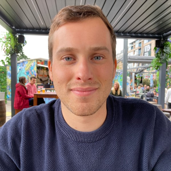 Headshot of alumnus, Barney Bennett. he is wearing a navy jumper and smiling at the camera.