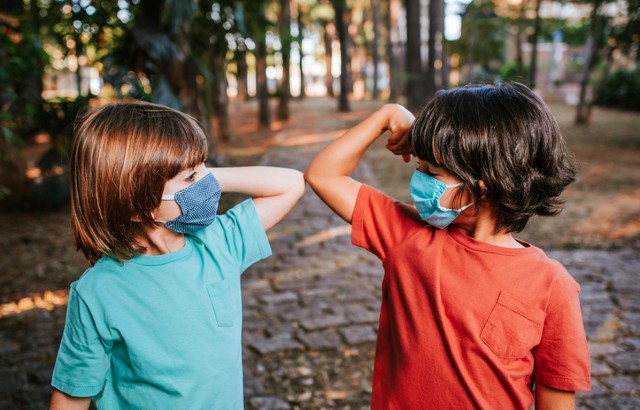 Two young boys wearing face coverings 'elbow bump' as an alternative handshake during the coronavirus pandemic.