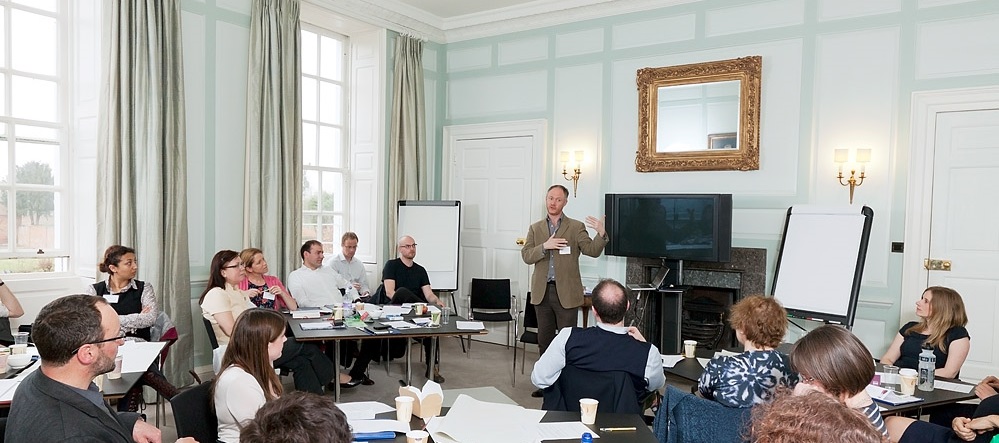 A large workshop with several attendees watching a facilitator