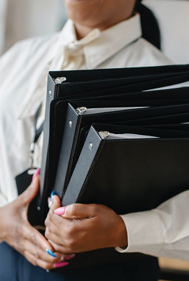 Photograph of a woman holding three black folders