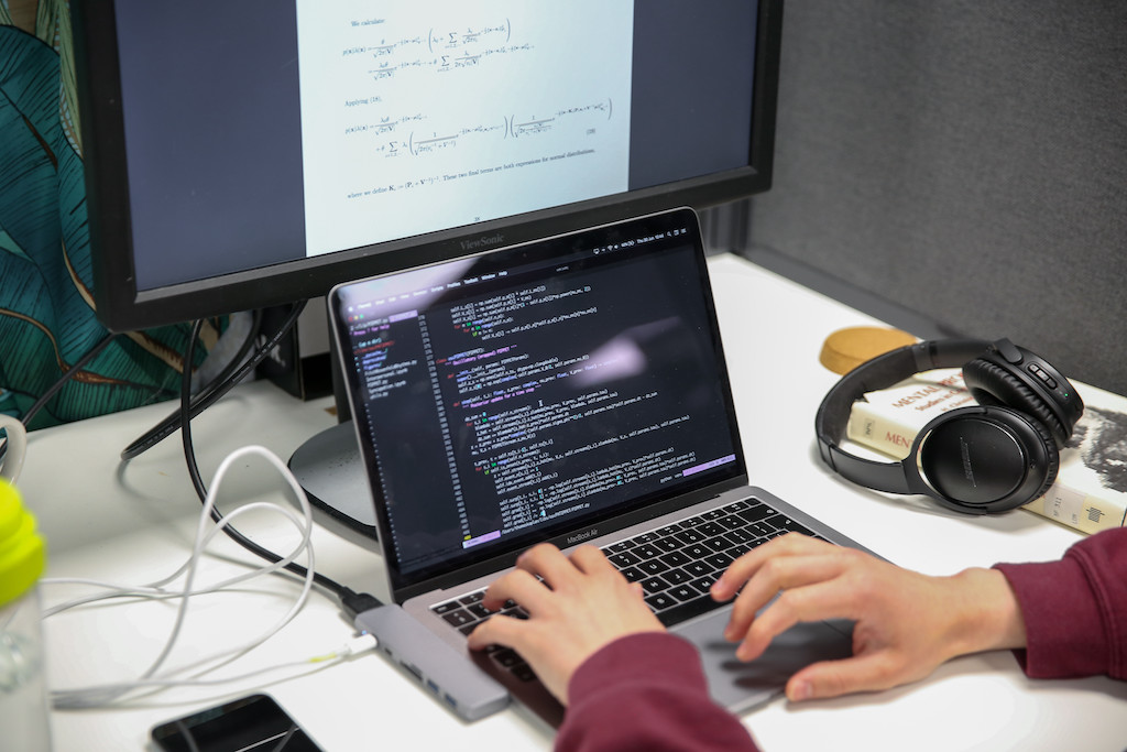 Hands typing code on a laptop