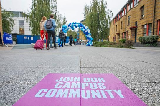 Students arriving on Campus with their suitcases and a sticker saying 