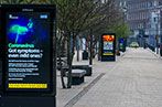 Street lined with bus shelters displaying COVID-19 warnings