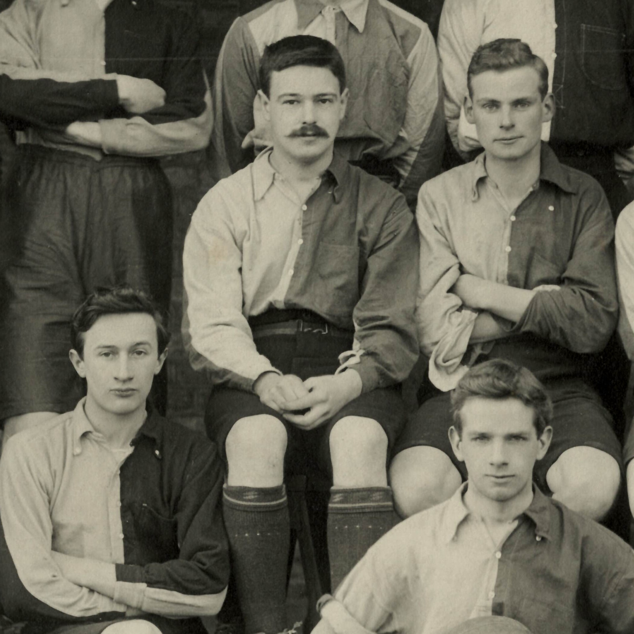 Photograph of boy in football kit with a moustache seated among teammates