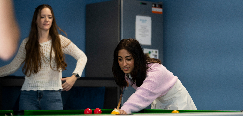 Student playing billiards pool in Malta common room