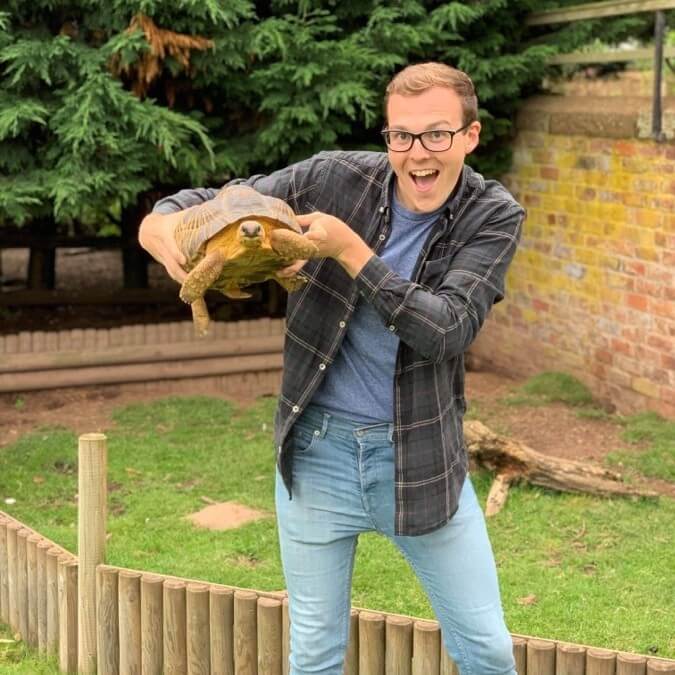 Alumnus Dan Harrold holding a tortoise