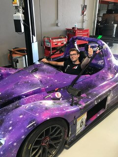 Alumnus Eathan Plaschka sitting in a Formula Student engineering car