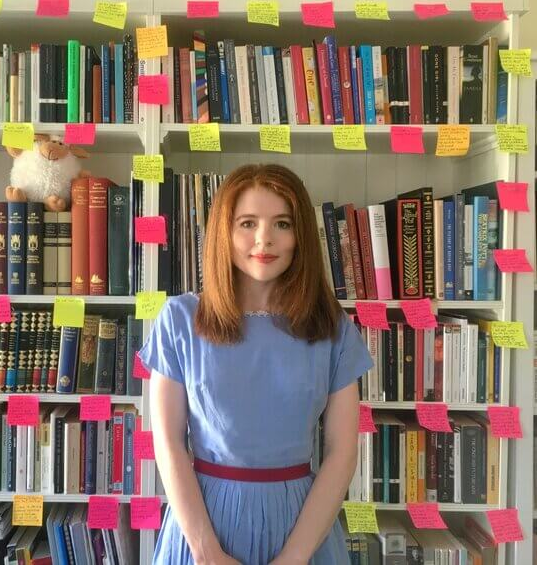 Headshot of alumna Isabel Biggs in front of her bookcase.