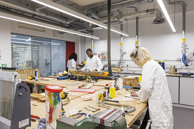 Three students at workbenches in an electronic engineering lab