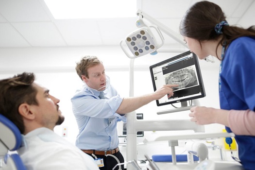 Dentist showing image to student and patient