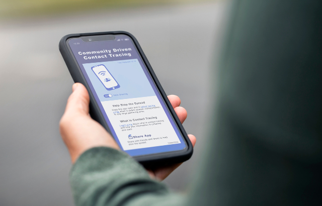 A woman holding her smartphone checking a contact tracing app. Credit:mphillips007/iStock.com