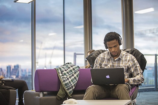 Student studying with MacBook and headphones