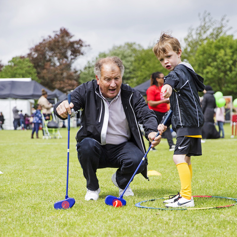 A man and young boy playing mini golf at the Festival of Communities