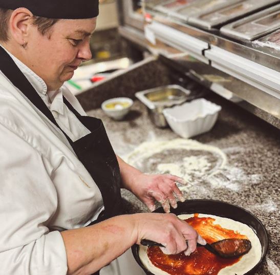 A Chef from Queen Mary's Curve Kitchen making a pizza base out of Angry Monk's surplus and wonky tomatoes.