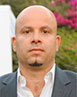 Dr Noam Shemtov standing in front of a hedge