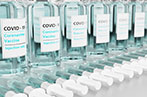 A row of Covid-19 vaccine vials with syringes