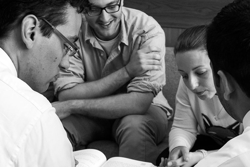 A black and white photograph of four people in discussion