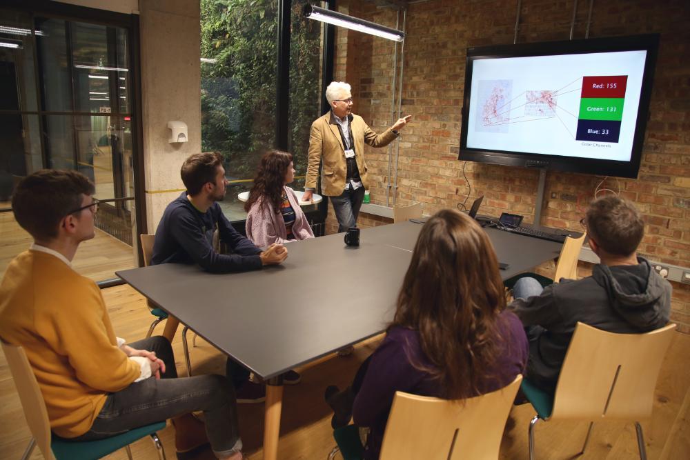 A group of people sitting at a table listening to a presentation