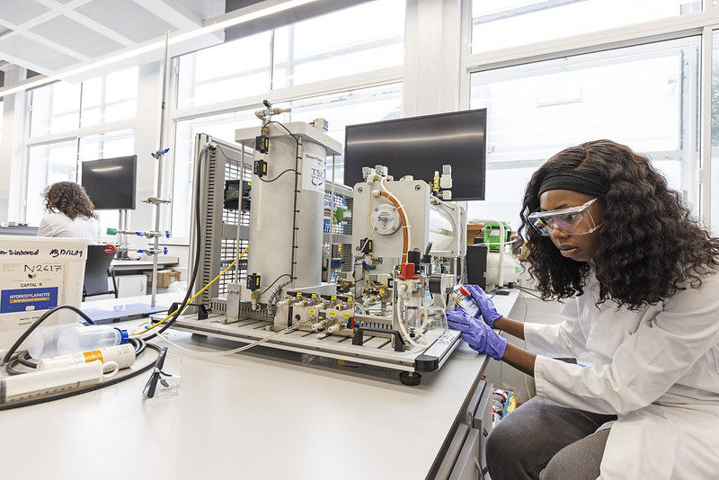 An engineering student in a workshop wearing safety glasses