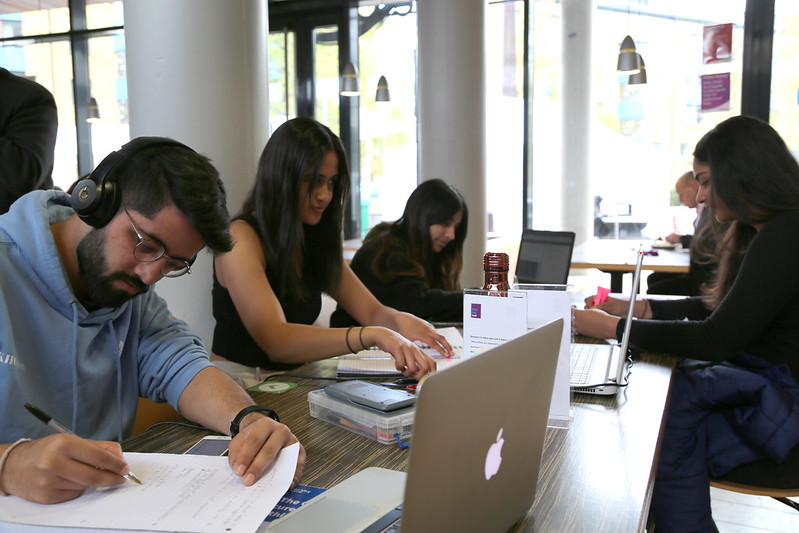 A group of students writing on paper and laptops