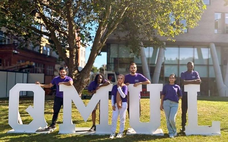 Queen Mary students with large white letters spelling QMUL