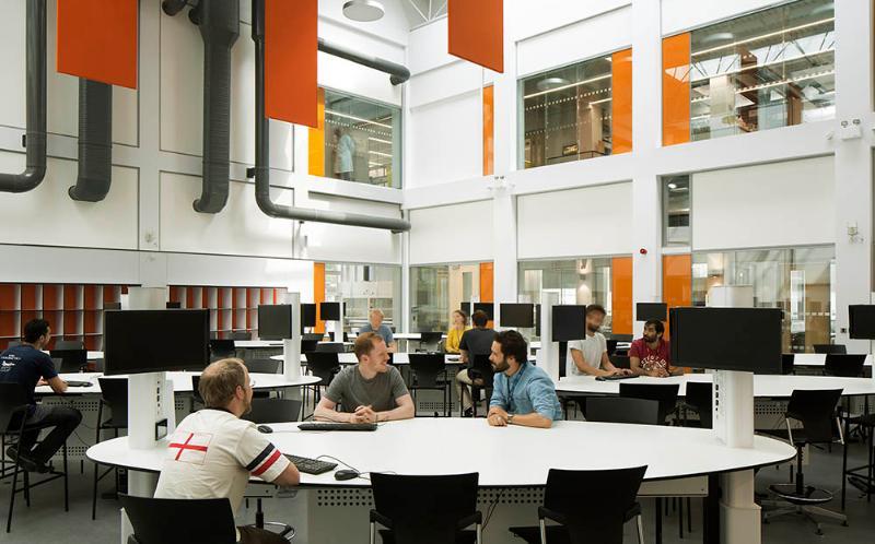 Three people sitting around a table in a large space